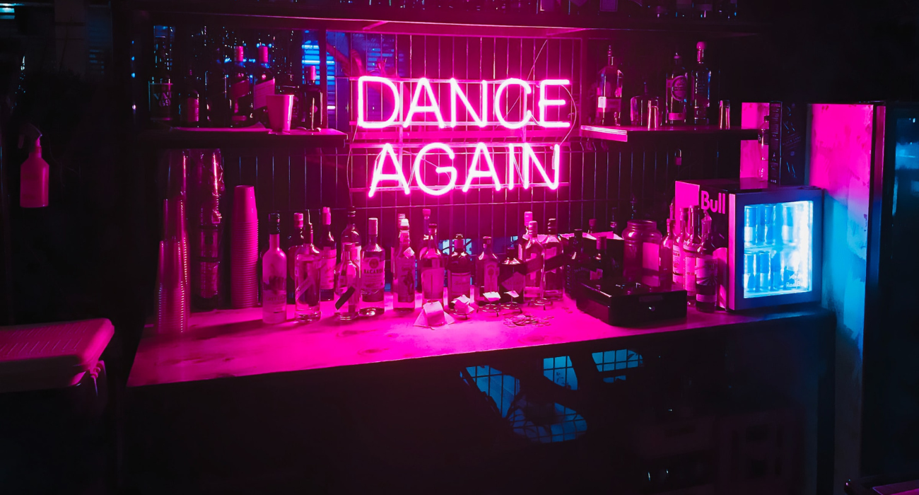 Bar met een neon bord met de woorden "dance again" .